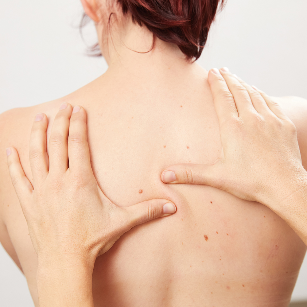 Rücken von hinten gesehen mit Händen darauf: Manuelle Therapie